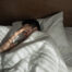 A man is lying in bed and holding his head with his hand