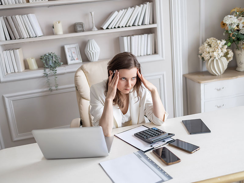 The woman tries to focus on her tasks and holds her head