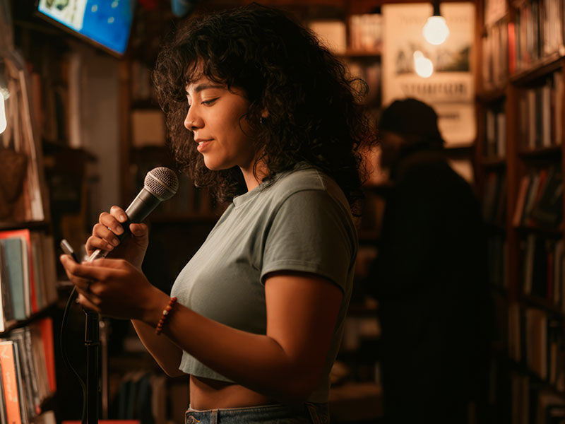 Mental-Health-and-Recovery-Friendly-Coffee-Shops-&-Spaces-in-Philadelphia-Suburbs-2 A girl with a microphone gives a lecture at a book club