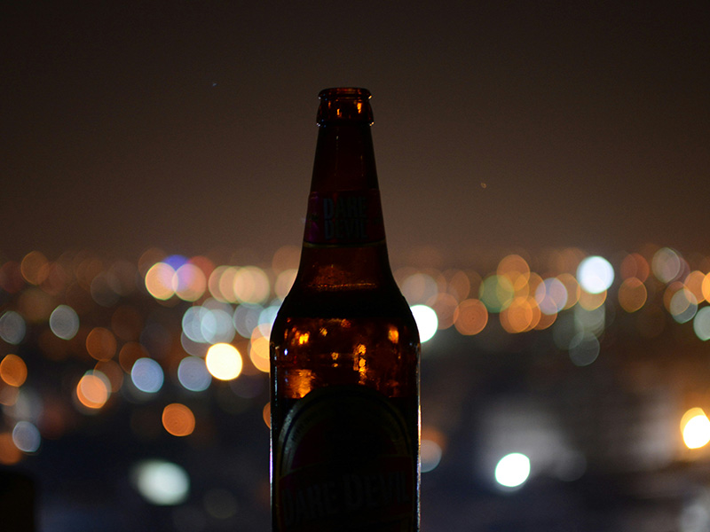 a bottle of alcohol on the background of a city at night where lights twinkle